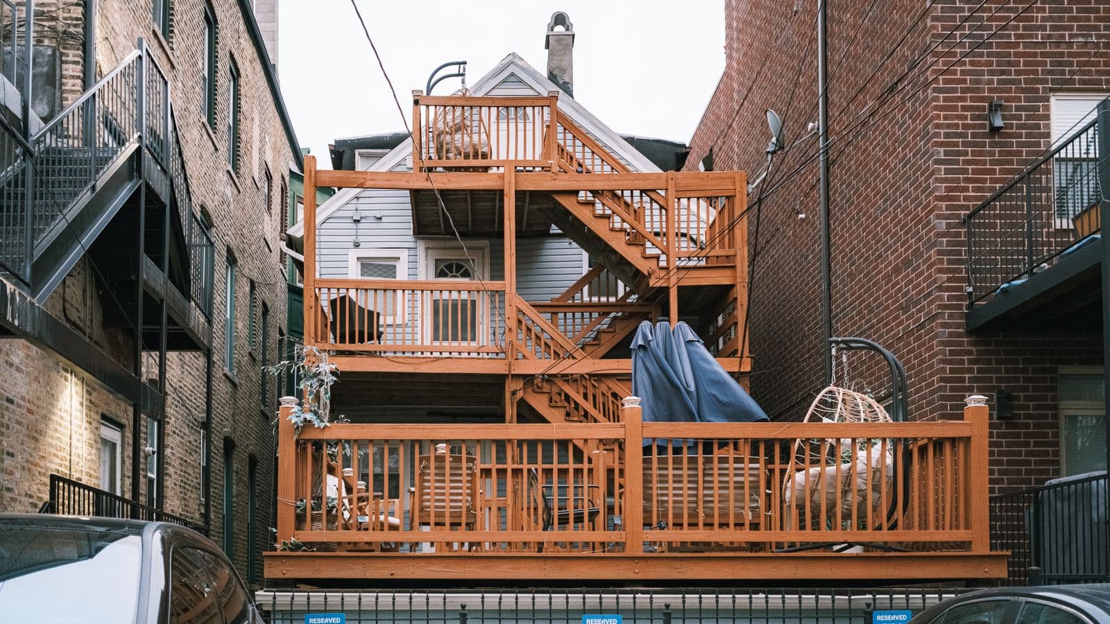 Multi-level wood deck and stairs on the back of a brick building