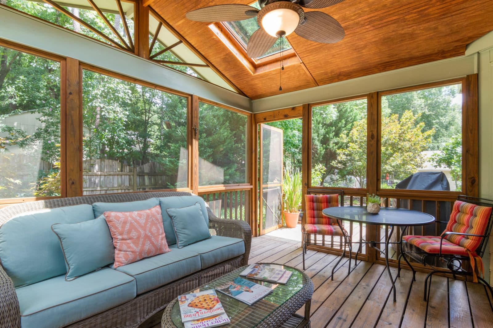 Screened porch with a vaulted wood ceiling, sofa and dining set